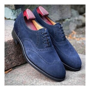 May include: A pair of blue suede leather oxford shoes with brogue detailing and lace-up closures.