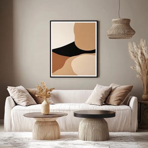 Può includere: Stampa d'arte astratta con uno schema di colori nero, marrone e beige. La stampa è incorniciata in una cornice nera e appesa a una parete beige.