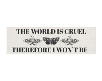 May include: Rectangular sign with the text "THE WORLD IS CRUEL THEREFORE I WON'T BE" in black. Three moth illustrations are between the text. The background is a light beige color.