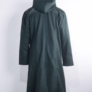 May include: A dark green hooded coat with a long, tailored design. The coat features a hood, structured shoulders, and detailed cuffs. The coat is displayed on a wooden hanger against a white background.