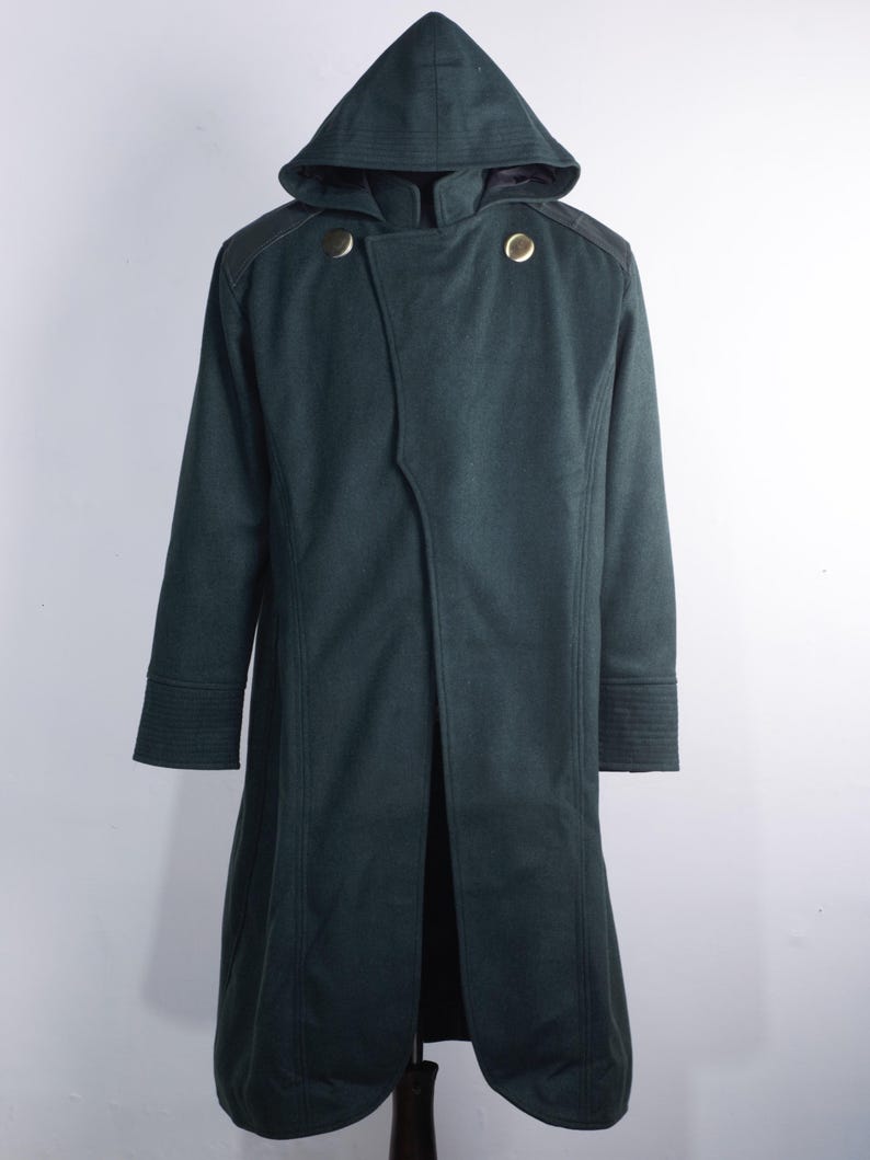 May include: A dark green hooded coat with a double-breasted design. The coat features two gold-colored buttons, shoulder accents, and a long, flowing silhouette. The sleeves have detailed cuffs.