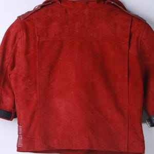 Puede incluir: Chaqueta de ante roja con cuello y detalles de cuero. La chaqueta presenta un estilo motero cl&aacute;sico con solapa de muesca, charreteras y detalle de cintur&oacute;n en la cintura. Las mangas tienen pu&ntilde;os negros.