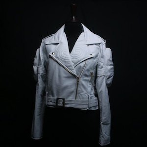 May include: A white leather motorcycle jacket featuring a wide notched collar with spiral quilted detailing, an asymmetrical gold-tone zip closure, long sleeves with shoulder epaulets, and a matching adjustable waist belt with a gold buckle.