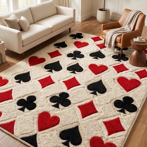 May include: A rectangular area rug featuring a repeating pattern of red hearts, red diamonds, black clubs, and black spades on a cream-colored textured background. The design mimics the suits found on a standard deck of playing cards.