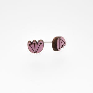 May include: A pair of pink wooden earrings with a flower design. The earrings are made of wood and have a pink stain. The flower design is simple and elegant.