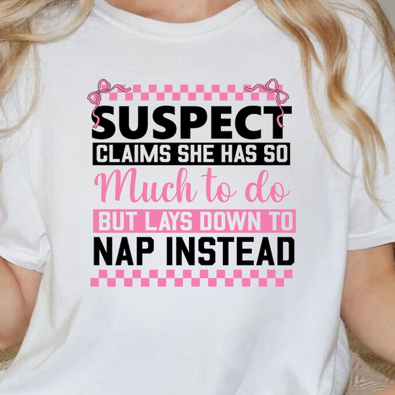 K&ouml;nnte beinhalten: Wei&szlig;es T-Shirt mit einer schwarzen und pinkfarbenen Grafik, auf der "SUSPECT CLAIMS SHE HAS SO MUCH TO DO BUT LAYS DOWN TO NAP INSTEAD" steht.