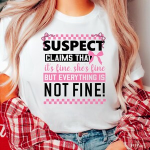 K&ouml;nnte beinhalten: Wei&szlig;es T-Shirt mit einer schwarzen und pinkfarbenen Grafik, auf der "SUSPECT CLAIMS THAT it's fine. she's fine BUT EVERYTHING IS NOT FINE!" steht.