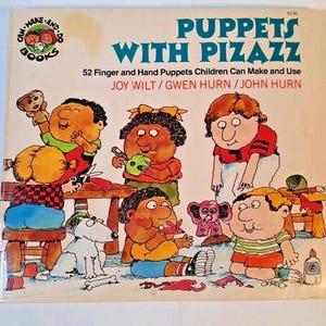 May include: A vintage book cover titled "Puppets With Pizazz" featuring colorful illustrations of children and puppets. The cover includes text that reads "52 Finger and Hand Puppets Children Can Make and Use" and the names of the authors.