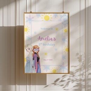 K&ouml;nnte beinhalten: Ein rechteckiges gerahmtes Poster mit zwei animierten Figuren, eine mit blondem Haar und eine mit rotbraunem Haar, die herzf&ouml;rmige Sonnenbrillen tr&auml;gt. Der Text lautet Welcome to Amelia's 5th birthday May 27 2029, umgeben von gelben Sonnen und blauen Schneeflocken.