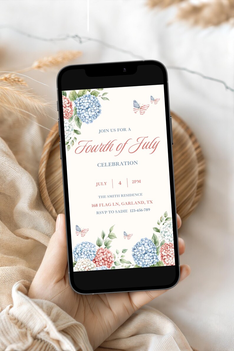 May include: A smartphone displays a Fourth of July invitation. The invitation features floral arrangements of blue and pink hydrangeas, with butterfly accents. The text reads "Join us for a Fourth of July Celebration" with date, time, and RSVP information.