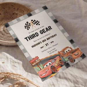 May include: A rectangular birthday invitation card featuring a checkered border, two checkered flags, and illustrations of two cartoon race cars. The text reads: It's time to kick it into THIRD GEAR, Race on over to celebrate HUDSON'S 3RD BIRTHDAY.