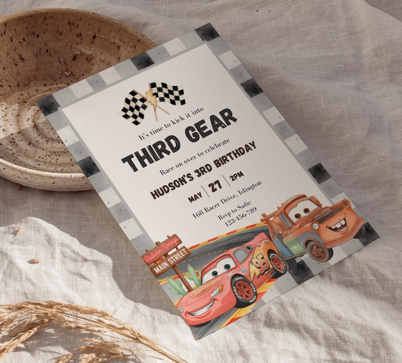 May include: A rectangular birthday invitation card featuring a checkered border, two checkered flags, and illustrations of two cartoon race cars. The text reads: It's time to kick it into THIRD GEAR, Race on over to celebrate HUDSON'S 3RD BIRTHDAY.