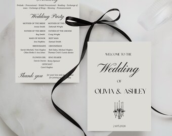 May include: Two wedding cards with black text and a black ribbon. One card lists the ceremony details and wedding party names. The other card says "Welcome to the Wedding of Olivia & Ashley" with the date 2.10.2028.