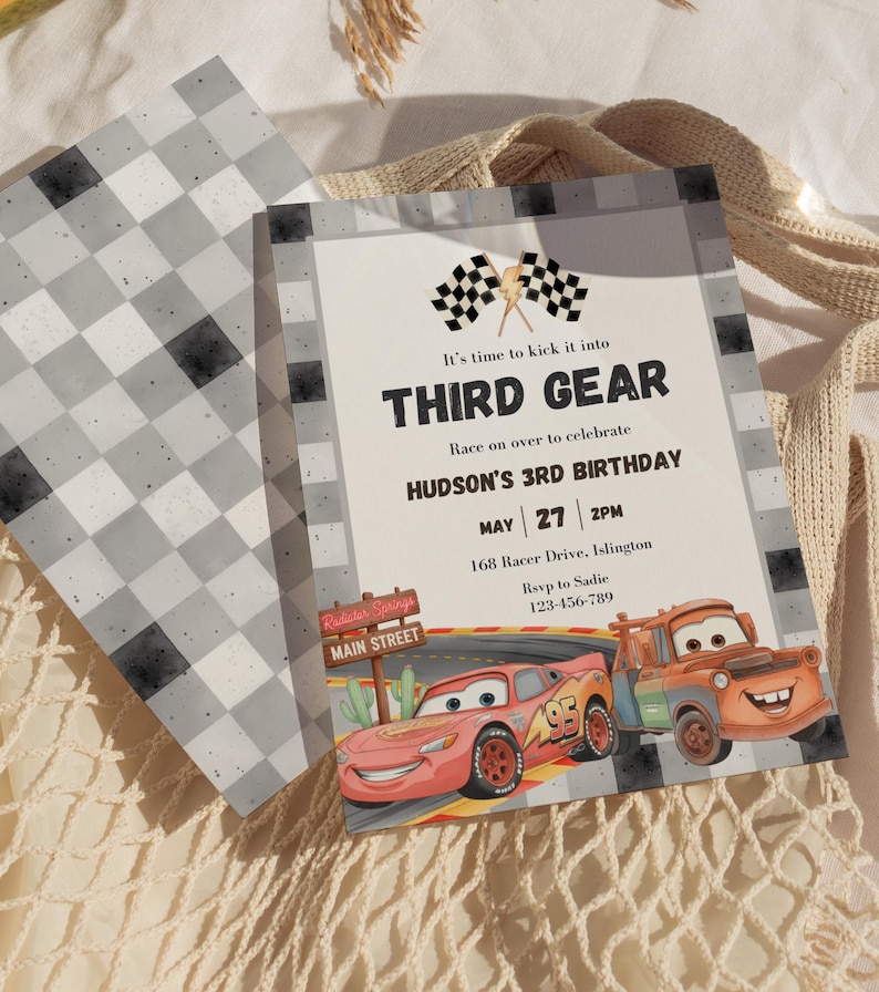May include: A rectangular birthday invitation card featuring a checkered border, two checkered flags, and a lightning bolt icon. The text reads: It's time to kick it into THIRD GEAR, Race on over to celebrate HUDSON'S 3RD BIRTHDAY, MAY 27 2PM, 168 Racer Drive, Islington, Rsvp to Sadie 123-456-789. A red race car and an orange tow truck are illustrated at the bottom.