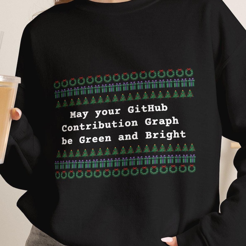 May include: A black long-sleeve sweatshirt featuring a holiday-themed pattern of wreaths, gift boxes, and Christmas trees. The center text reads: May your GitHub Contribution Graph be Green and Bright, printed in white, sans-serif lettering.