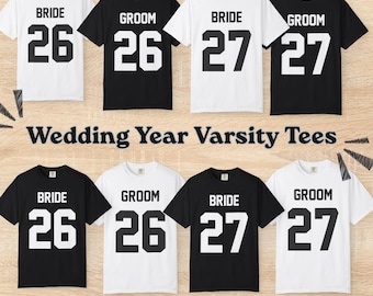 Könnte beinhalten: Acht kurzärmelige T-Shirts in Schwarz und Weiß, angeordnet in zwei Reihen. Jedes T-Shirt zeigt den Text BRIDE oder GROOM über den Zahlen 26 oder 27 in einer Varsity-Schriftart. Der Text Wedding Year Varsity Tees ist zentriert.