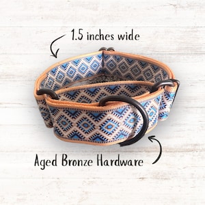 May include: A pet collar featuring a geometric diamond pattern in shades of blue, tan, and white. The collar is 1.5 inches wide and includes aged bronze hardware, specifically a D-ring and a slider, as indicated by the text in the image.