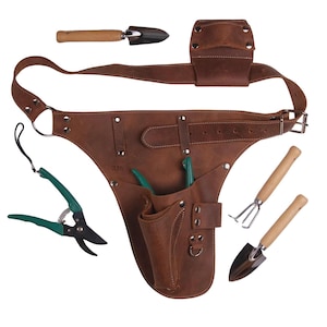 Op de afbeelding: Een bruine leren tuingereedschapsriem met meerdere zakken en een riem. Inclusief een snoeischaar met groene handgrepen, een kleine troffel, een handhark en een kleine schop. De riem is ontworpen om om de taille te worden gedragen.