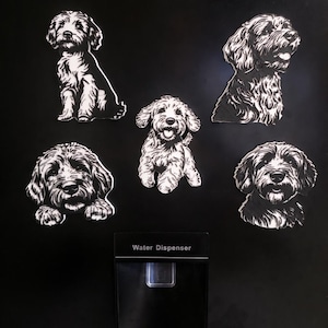 May include: A collection of black and white dog stickers, each showing a different pose of a fluffy dog breed. The stickers are on a black background, with a water dispenser visible below. The dogs have detailed fur.