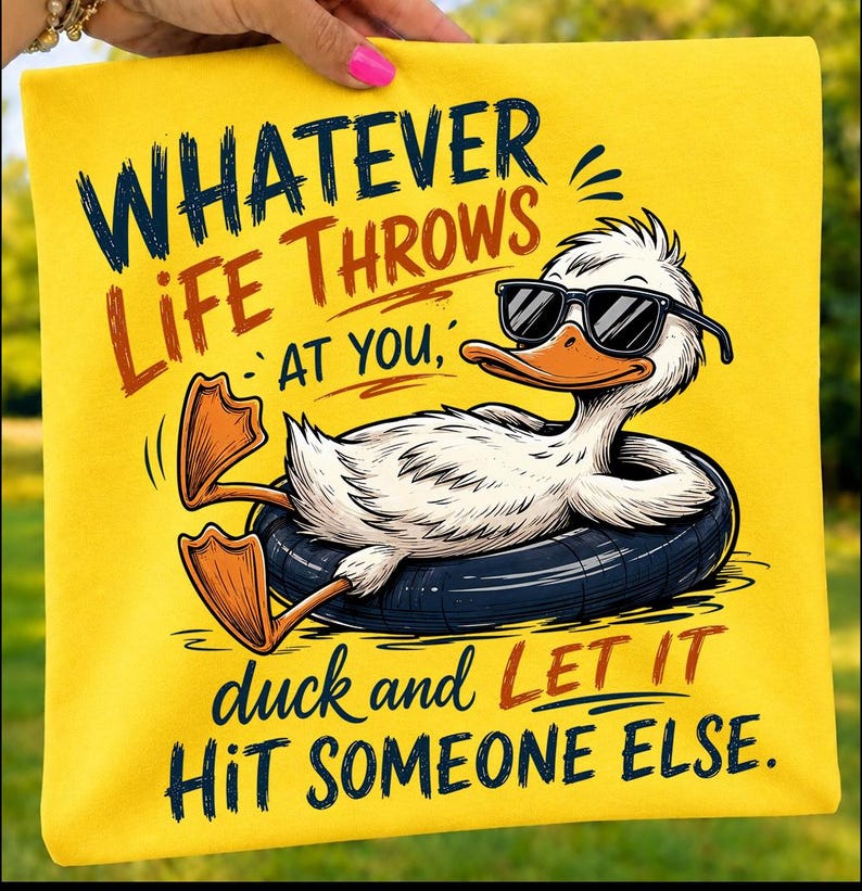 Folded yellow t-shirt mockup featuring a cool cartoon duck floating in a black tube with sunglasses and the humorous quote "Whatever Life Throws At You, Duck and Let It Hit Someone Else," perfect for funny summer and casual gifts.