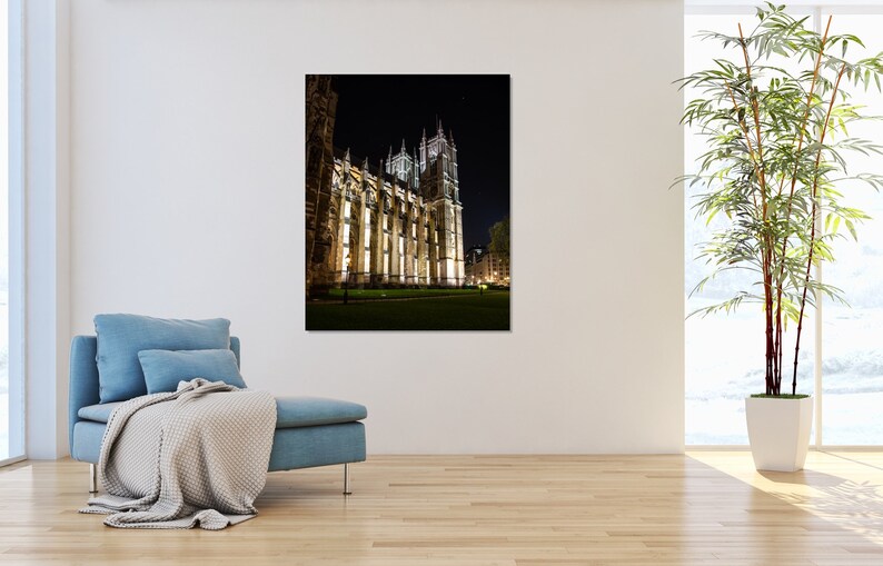 May include: A night view of a large, illuminated stone building with a tall spire. The building is surrounded by a grassy lawn and trees.