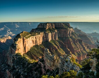 May include: A panoramic view of the Grand Canyon, showcasing the layered rock formations and the vastness of the canyon. The image captures the natural beauty of the canyon, with its deep, rugged cliffs and the lush vegetation growing on the edges.
