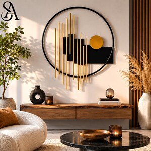 May include: A circular wall art piece featuring a black metal frame, vertical gold rods, black rectangular panels, and a solid gold circle. The design is mounted on a wall above a wooden console table with various decorative items and a coffee table.