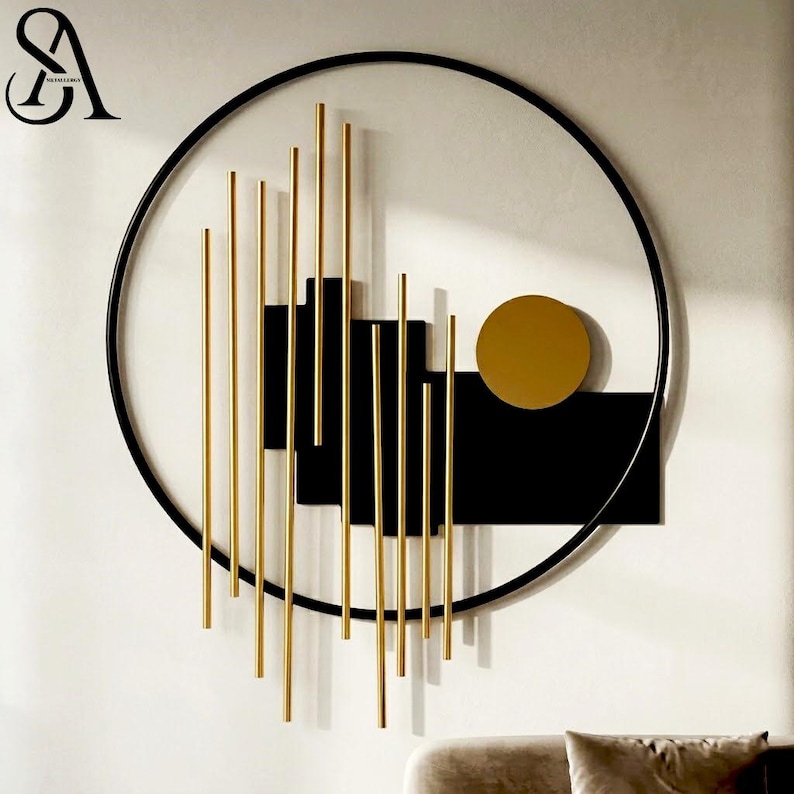 May include: A circular wall art piece featuring a thin black metal frame enclosing a series of vertical gold-toned rods of varying lengths, layered over solid black rectangular panels and a single solid gold-toned circle on the right side.