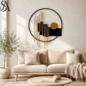May include: A circular wall art piece featuring a black metal frame, vertical gold rods of varying lengths, black rectangular panels, and a solid gold circle. The design is abstract and geometric, mounted on a plain wall above a beige sofa.
