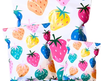 May include: White packaging bags with a colorful strawberry pattern. The strawberries are in various colors, including pink, orange, yellow, blue, and green. The bags are in different sizes and are likely for packaging gifts or products.