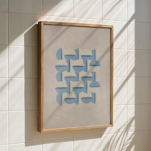 Pode incluir: Uma obra de arte emoldurada com um fundo bege e um padrão repetitivo de formas geométricas azuis claras. A obra de arte está em uma moldura de madeira natural e é montada em uma parede de azulejos brancos.