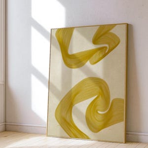Puede incluir: Impresión artística abstracta con dos formas fluidas, similares a cintas, en un tono amarillo dorado sobre un fondo crema. La obra está enmarcada en un marco fino de color dorado, apoyada contra una pared blanca. La pieza evoca una sensación de movimiento y fluidez.