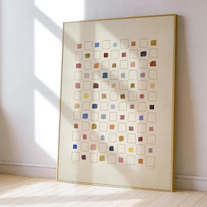 以下が含まれることがあります： 金色の枠線の中にカラフルな正方形のグリッドが描かれた抽象的なアートプリント。正方形は、青、赤、黄、茶色など様々な色で塗りつぶされ、クリーム色の背景に配置されています。アートワークは金色のフレームに額装されています。