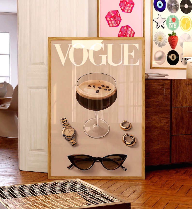 Puede incluir: Un p&oacute;ster beige con la palabra "VOGUE" en letras blancas. El p&oacute;ster presenta un vaso de caf&eacute; con granos de caf&eacute; en la parte superior, un reloj dorado, un par de aretes dorados y un par de gafas de sol negras.