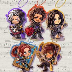 May include: Five acrylic charm standees featuring chibi-style characters from Clair Obscur: Expedition 33. The characters include a keyboardist, a figure with a red rose, a lute player, a character with a frame, and one with floating cards.