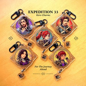 以下が含まれることがあります： Expedition 33 Hero Charmsのキーホルダーのコレクション。各透明アクリルチャームは、金色のダイヤモンドフレーム内にキャラクターの肖像画が描かれています。キーホルダーには黒い留め金と小さな正方形のチャームが付いています。「EXPEDITION 33」と「For The Journey Ahead」の文字が含まれています。