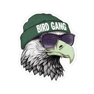 May include: A sticker featuring a stylized eagle head wearing a green beanie with the text "BIRD GANG" in white. The eagle is also wearing purple-framed sunglasses with a starry sky design.