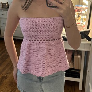 Puede incluir: Top de crochet rosa claro sin tirantes con dobladillo festoneado. El top presenta un diseño de corte horizontal cerca del abdomen. El top se combina con una falda vaquera azul claro.