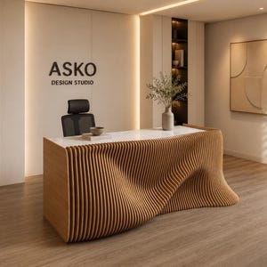 May include: A modern office reception area featuring a wooden reception desk with a distinctive, wave-like design. The wall behind the desk displays the text "ASKO DESIGN STUDIO". A black office chair is positioned behind the desk. The room has a minimalist aesthetic.