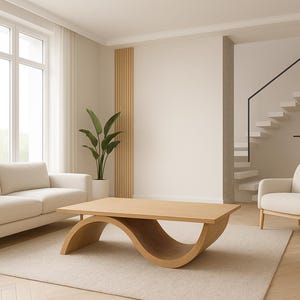 May include: A modern living room with a light color palette. A beige sofa and armchair are arranged around a unique wooden coffee table with a curved base. A large window and a staircase are visible.