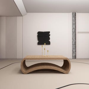 May include: A modern living room with a light wood coffee table and gold candle holders. A black abstract art piece hangs on the wall. The room has a neutral color palette with a curved design on the floor.