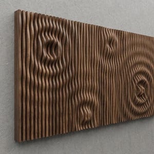 Op de afbeelding: Een rechthoekig houten wandkunstwerk met een getextureerd, gesneden ontwerp. Het kunstwerk heeft verticale lijnen en cirkelvormige patronen, waardoor een driedimensionaal effect ontstaat. Het hout heeft een warme, natuurlijke bruine tint.
