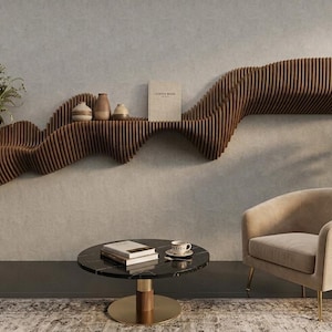 May include: A contemporary living room with a distinctive, undulating wooden shelf on a grey wall. The shelf displays vases, books, and flowers. A circular coffee table, armchair, and potted plant complete the stylish interior design.