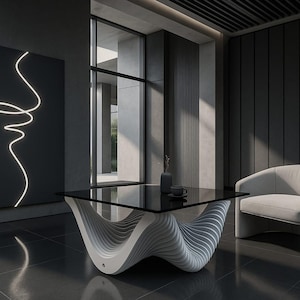 Puede incluir: Un salón moderno con una mesa de centro con tapa de cristal negro y una base blanca única en forma de ola. Un sillón blanco está cerca. Una obra de arte mural negra con un contorno de rostro de neón blanco cuelga en la pared.