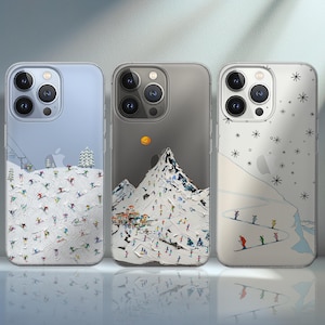 May include: Three clear phone cases with winter-themed designs. One case features skiers on a snowy slope, another shows a mountain scene with a sun, and the third has skiers on a slope with snowflakes.