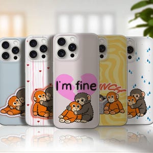 Puede incluir: Una colección de fundas para teléfonos con varios diseños. Cada funda presenta una ilustración de un mono de dibujos animados. Una funda tiene el texto "I'm fine" dentro de un corazón roto. Otras fundas tienen patrones de corazones, gotas de lluvia y líneas onduladas.