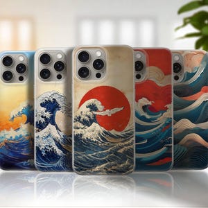 May include: A collection of phone cases featuring a Japanese wave design with a red sun. The cases display a variety of colors, including blue, orange, and red, and are designed to fit a smartphone. The cases are lined up in a row.