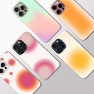 May include: Five smartphone cases featuring gradient and aura-style designs. The cases display various colour combinations including mint green to pink, solid orange, white with pink circular spots, and white with a central yellow aura effect.