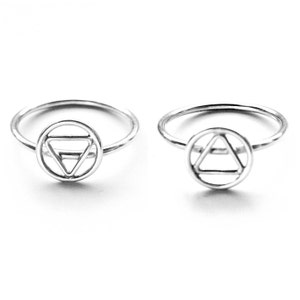May include: Two silver rings with a circle design featuring a triangle inside. The triangle is made of three lines that intersect to form a smaller triangle in the center.