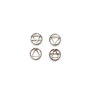 May include: Four silver charms with different geometric designs. Each charm is a circle with a different symbol inside. The symbols are a triangle, a circle, a square, and a star.